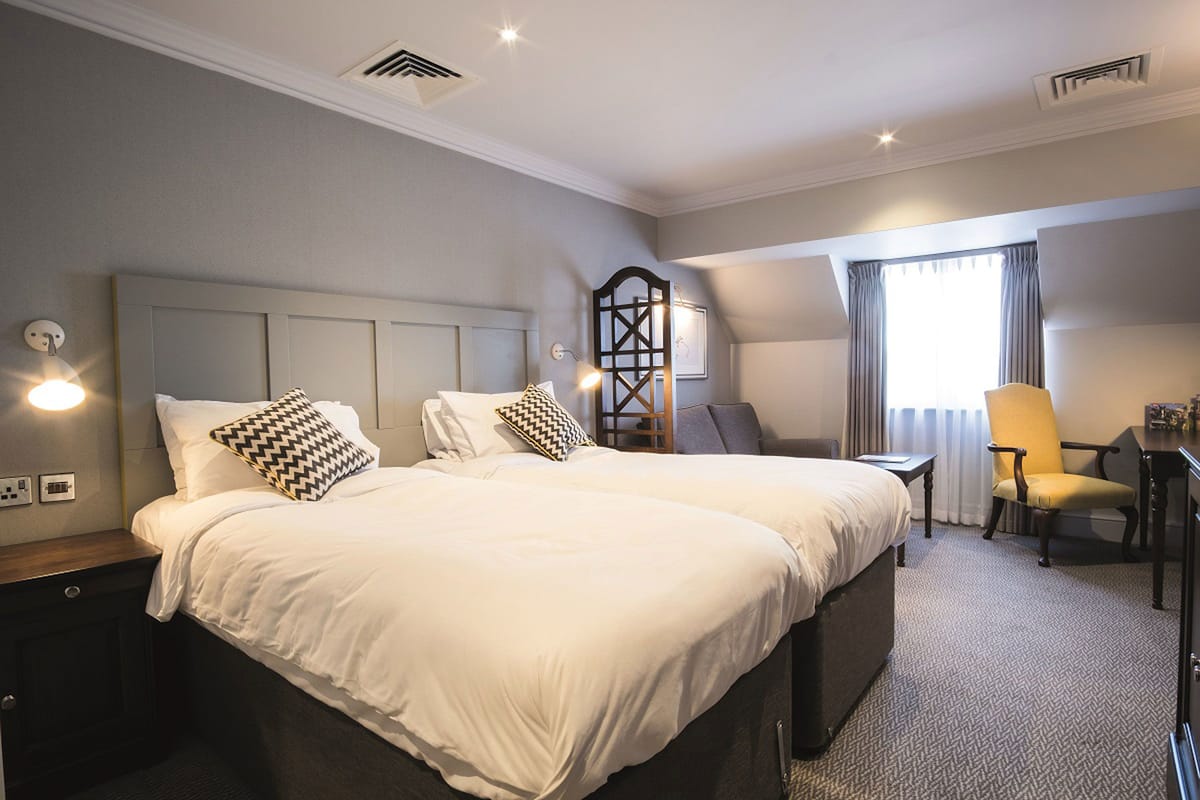 Una habitación de hotel con una cama grande, un escritorio, una silla y una ventana con cortinas.