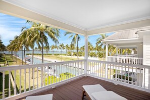 A covered balcony with white railings, wooden flooring, and two white lounge chairs. - Indigo Reef Resort Villas & Marina by KeysCaribbean (Marathon)
