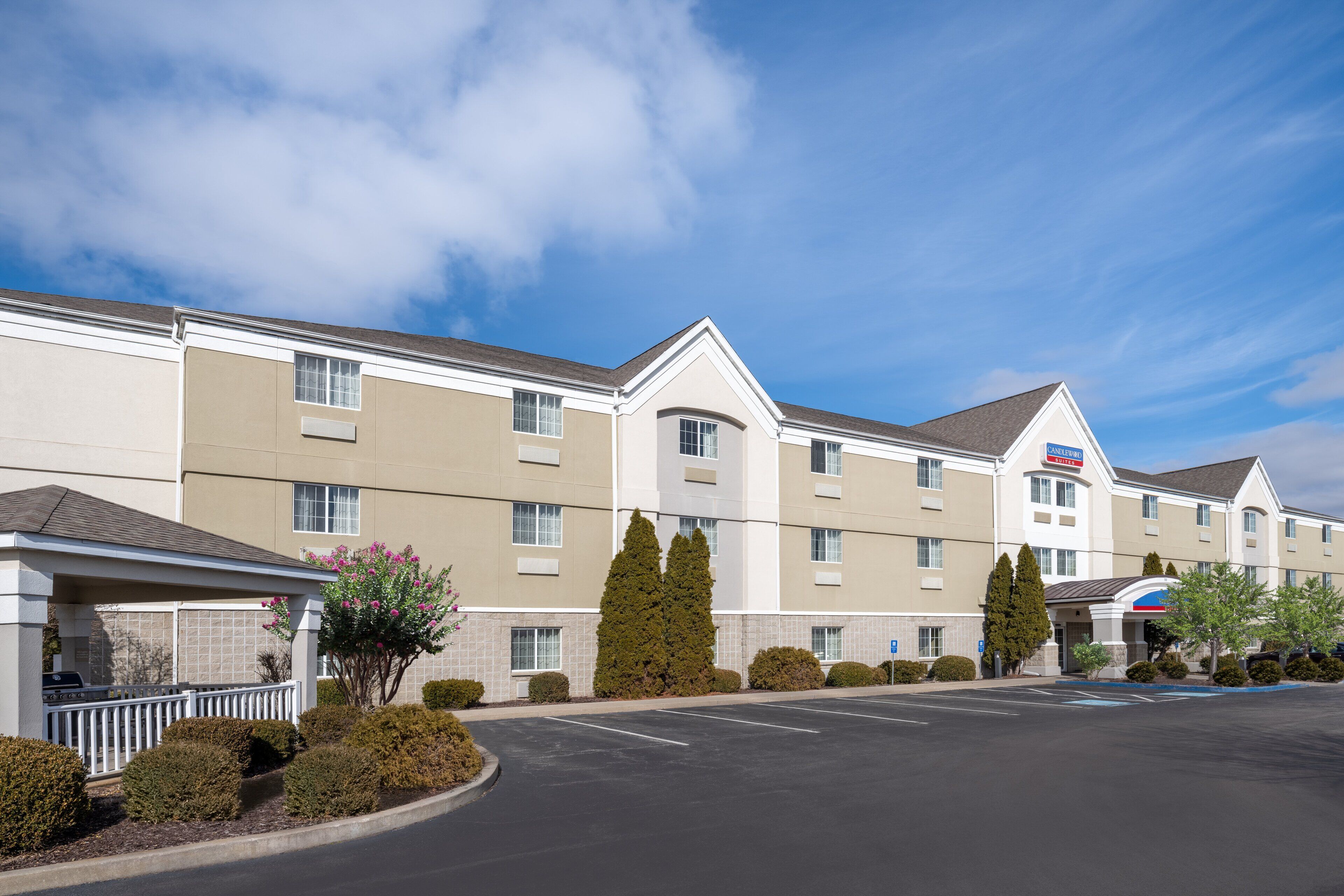 A multi-story hotel with a parking lot and a covered walkway.