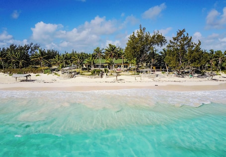 On the beach, white sand, sun-loungers, beach towels. Greenwood Beach Resort