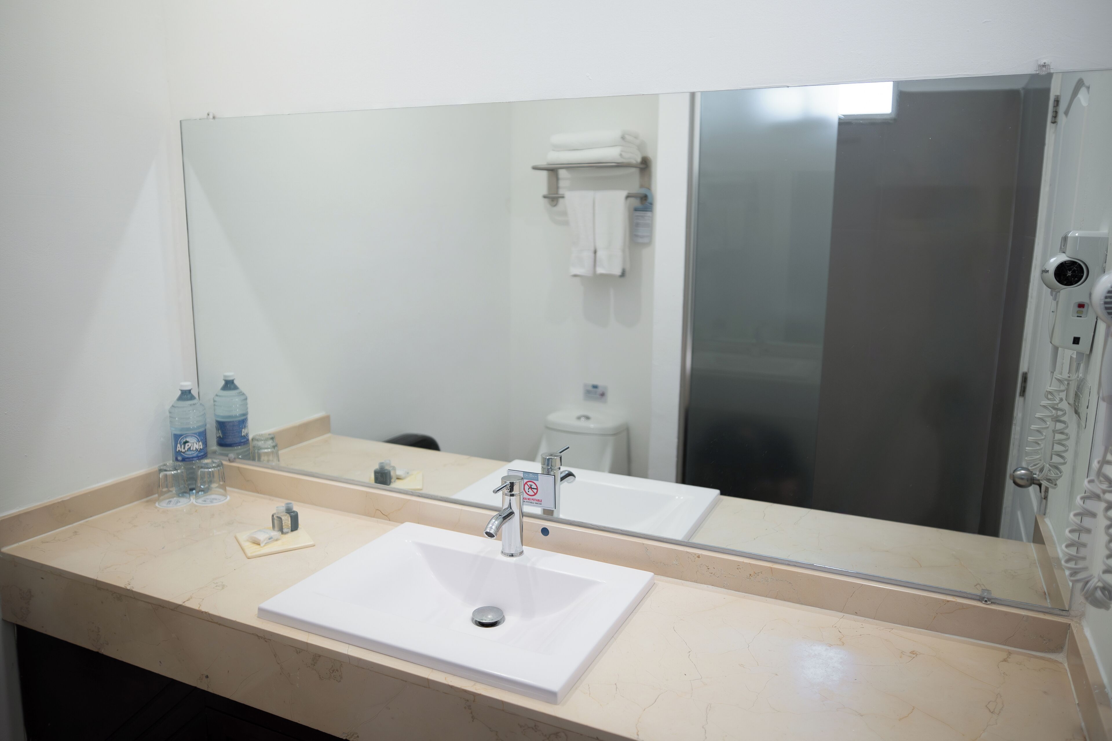 Ein Badezimmer mit einem weißen Waschbecken, einem Spiegel und einer Duschkabine.