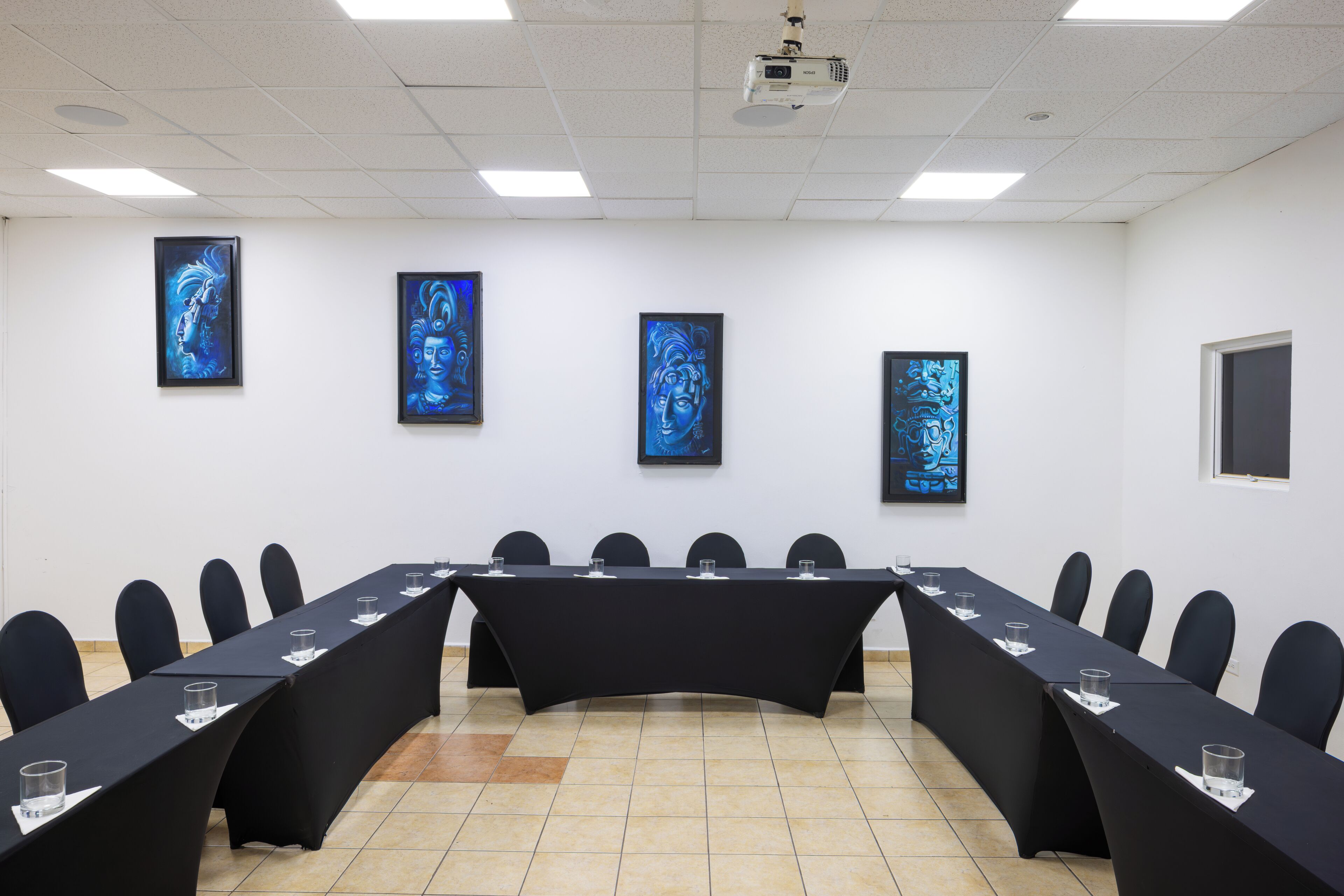 A conference room with a long table, chairs, and framed artworks on the walls.
