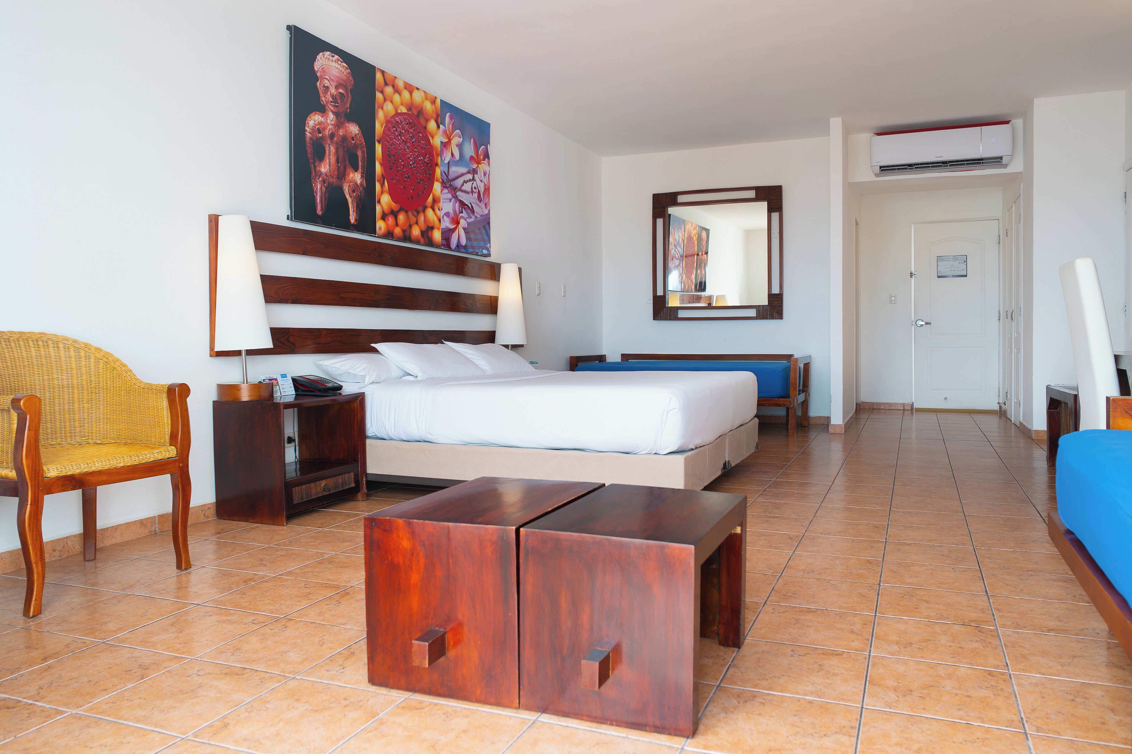 Ein Hotelzimmer mit Bett, Nachttisch, Lampe, Sessel und einem Gemälde an der Wand.