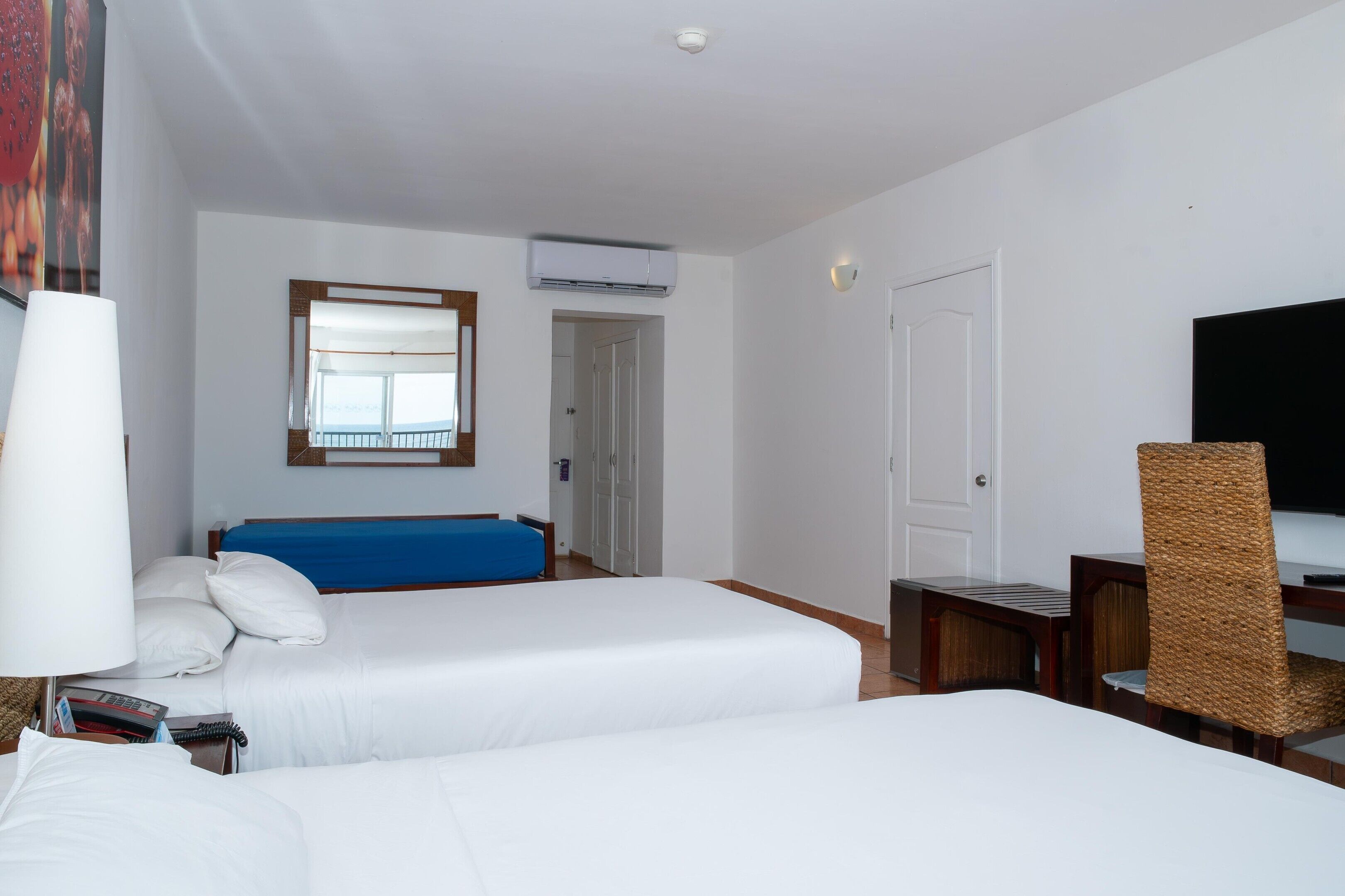 Une chambre d’hôtel avec deux lits, une télévision, un bureau et une fenêtre donnant sur un paysage agréable.