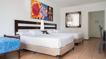 Habitación de hotel con dos camas, un cuadro grande sobre el cabecero, un espejo en la pared y una puerta a la derecha.
