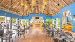 Un restaurante espacioso con techos altos, lámparas colgantes de mimbre y una zona de bufé.