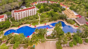 A resort with multiple swimming pools, a large building with balconies, and surrounding lush greenery.