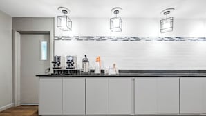 A modern kitchen with a large island, white cabinetry, and a tiled backsplash. - MainStay Suites Decatur River City (Decatur)
