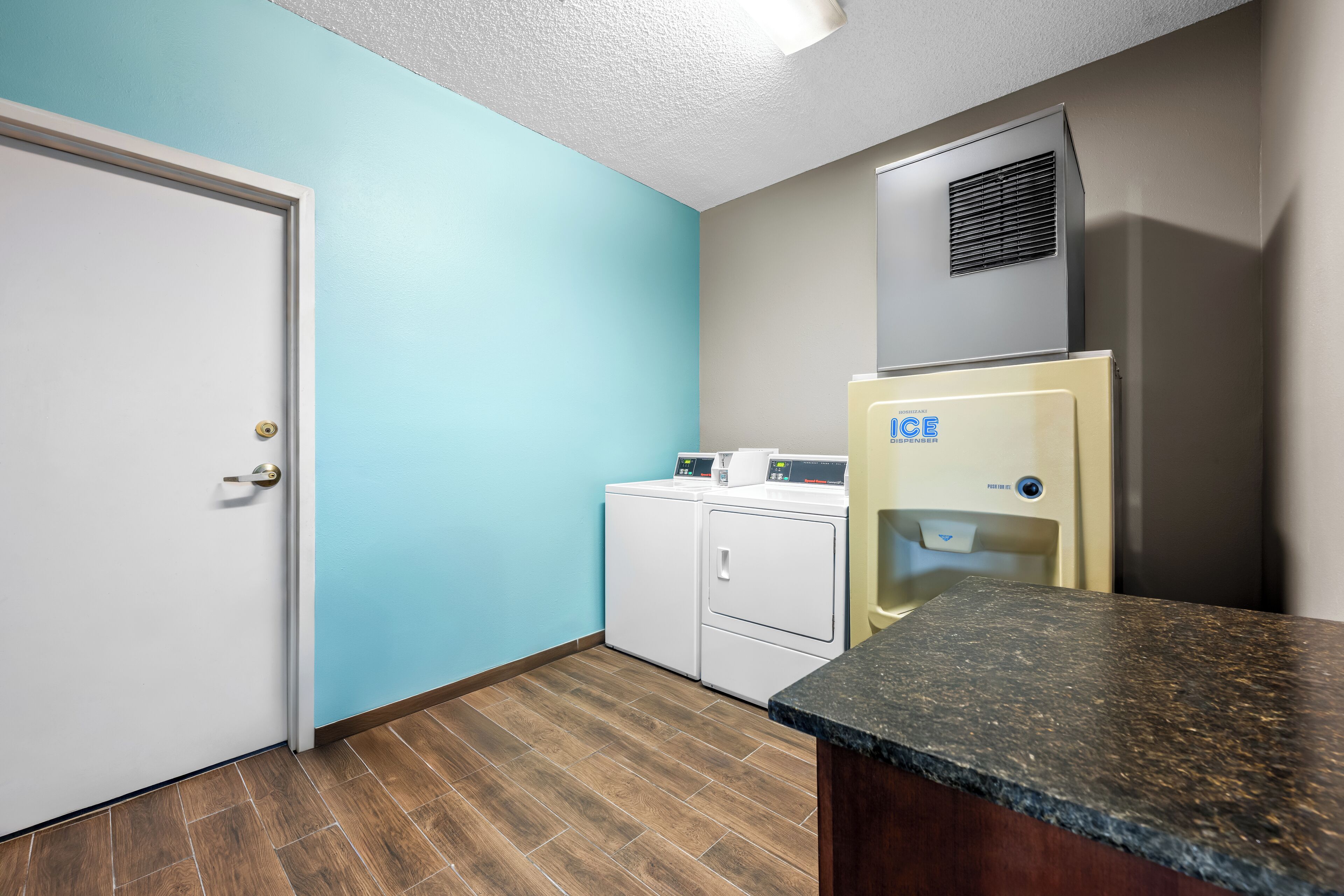 A laundry room with a white door, a washing machine, a dryer, and a water heater.