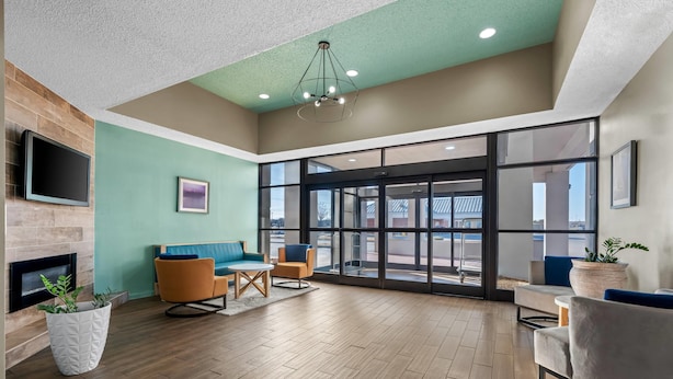 A spacious lobby with a fireplace, seating area, and large windows offering views of the outside. - MainStay Suites Decatur River City (Decatur)