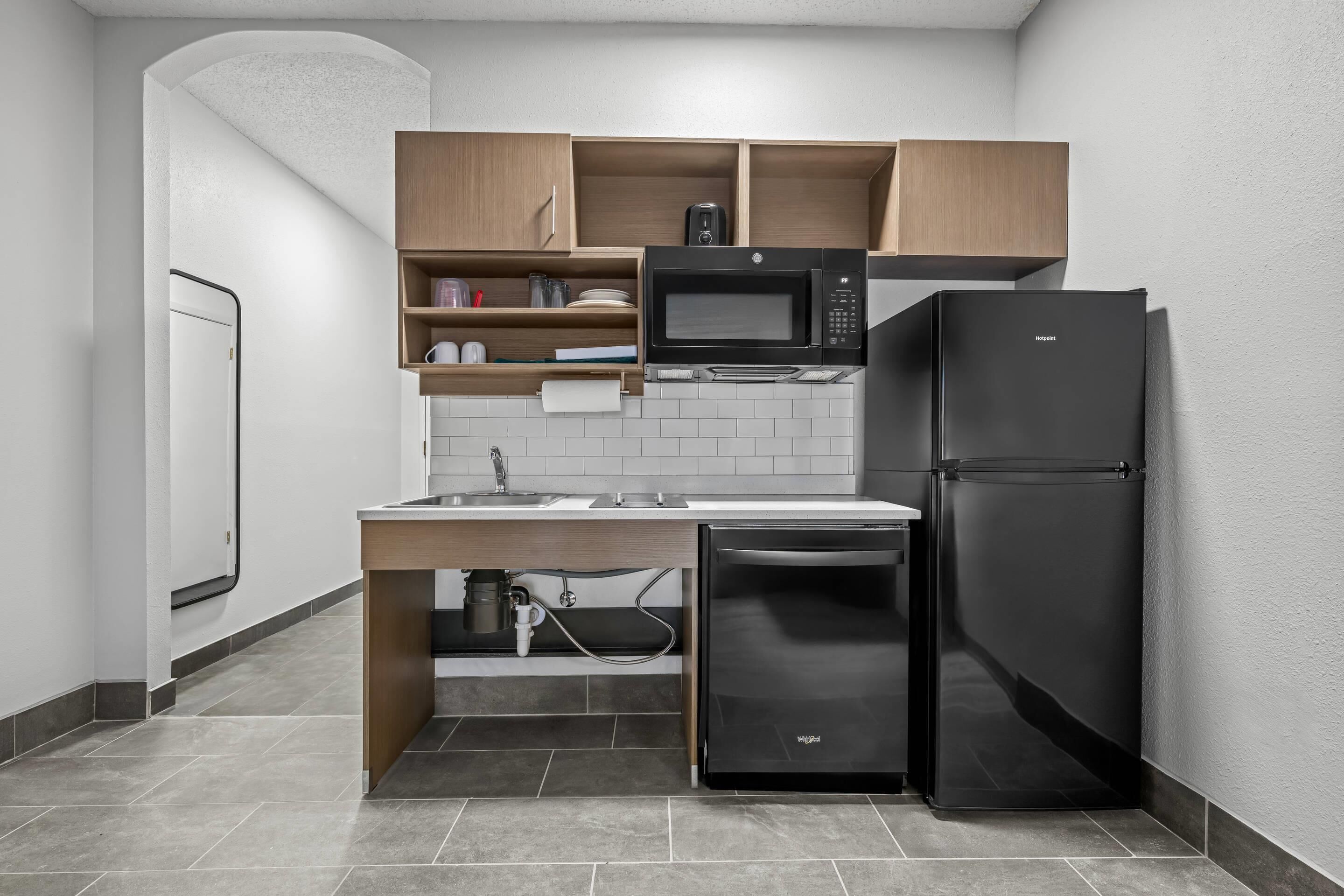 Eine kleine Küche mit Mikrowelle, Kühlschrank und Holzschränken.