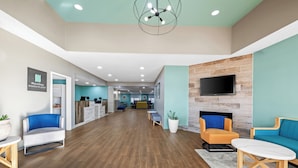 A spacious lobby with a wooden floor, seating areas, a mounted TV, and a reception desk. - MainStay Suites Decatur River City (Decatur)