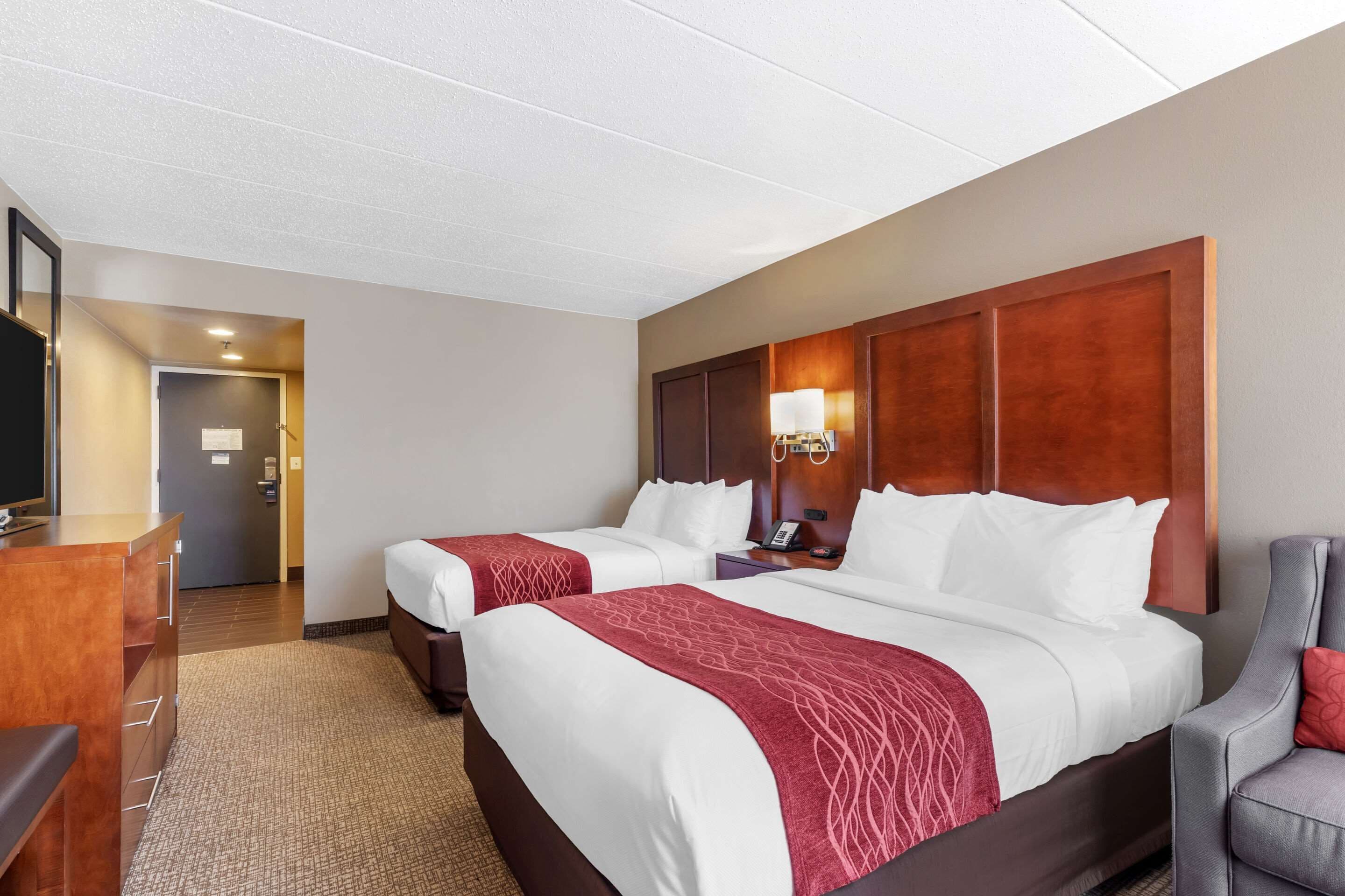 A hotel room with two beds, a desk, and a chair.