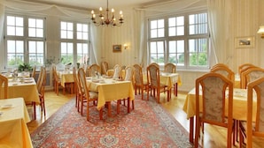 A dining room with multiple tables and chairs, large windows, and a chandelier. - Hotel Bellmoor Im Dammtorpalais (Hamburg)