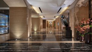 A modern hotel lobby with a marble floor, large columns, and a central staircase. - Pullman Shanghai Jing An (Shanghai)