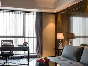 A modern hotel room with a sofa, a desk with a chair, a lamp, and a vase with flowers. - Pullman Shanghai Jing An (Shanghai)