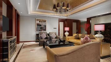 Una sala moderna con un sofá, sillones, una mesa de centro, televisor, candelabro y un espejo decorativo.