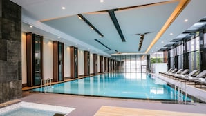A modern indoor swimming pool with a long, narrow design, surrounded by lounge chairs and a glass wall. - Pullman Shanghai Jing An (Shanghai)