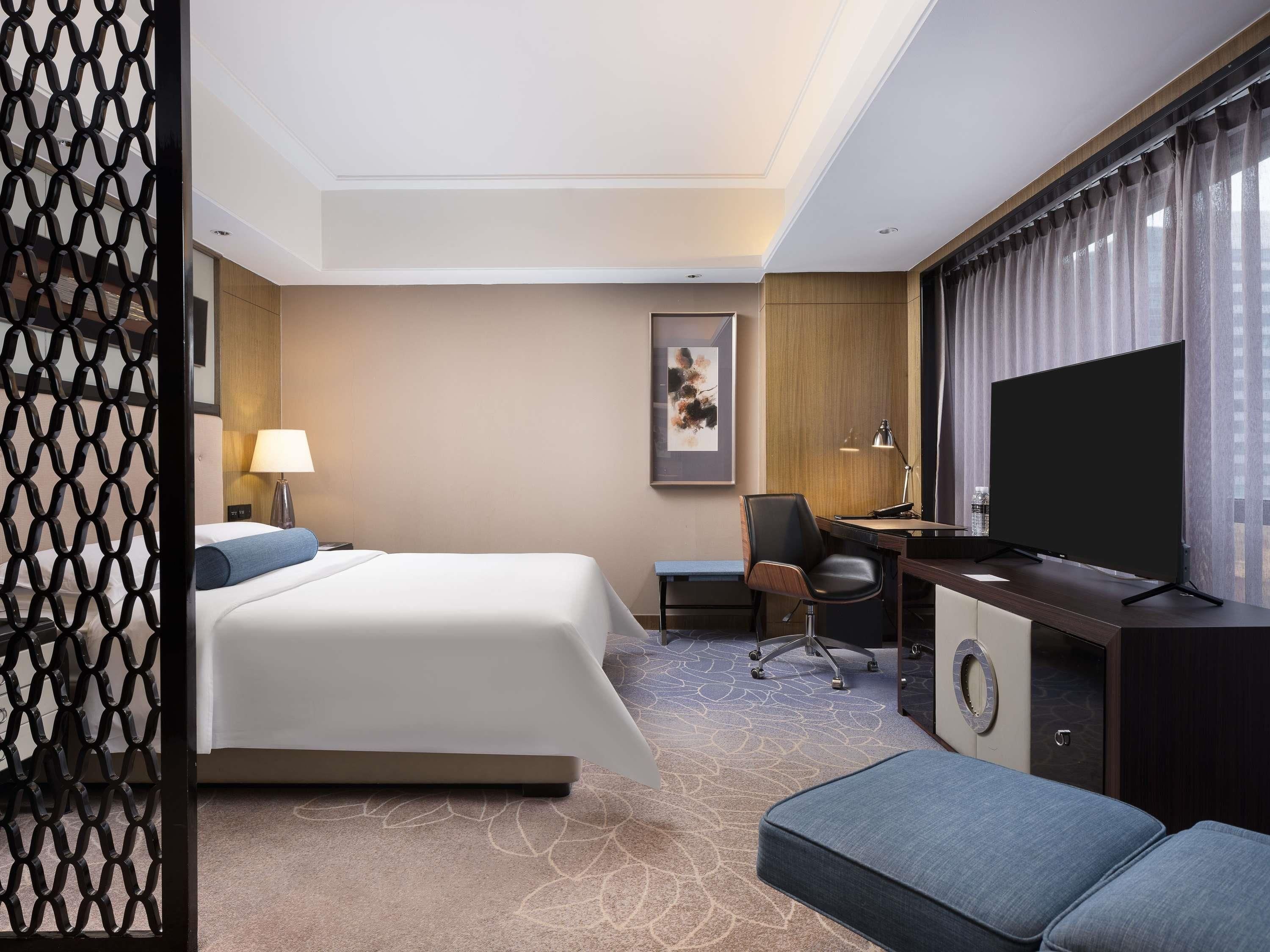 Een hotelkamer met een bed, bureau, stoel en televisie.