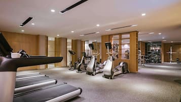 A modern gym with treadmills, elliptical machines, and weight equipment.
