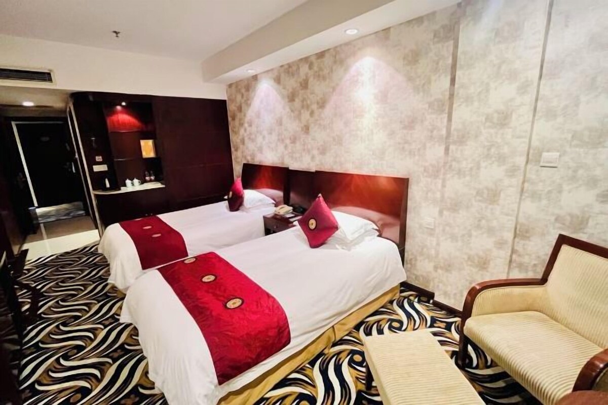 A hotel room with two beds, a sofa, and a patterned carpet.