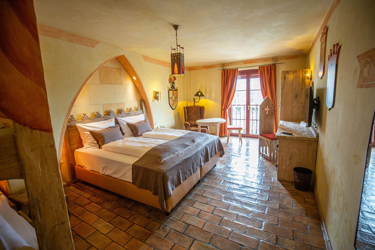 A cozy bedroom with a large bed, a small table, and a chair.