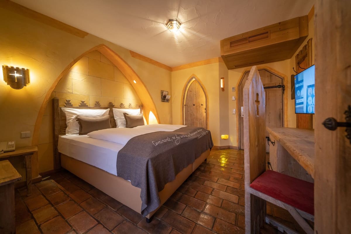 A cozy room with a bed, wooden door, and a television on the wall.