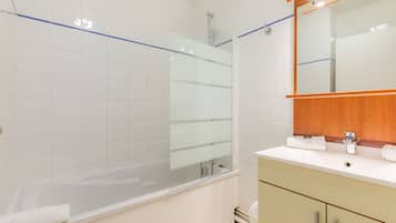 A modern bathroom with a glass-enclosed shower, a white sink, and a wooden vanity.
