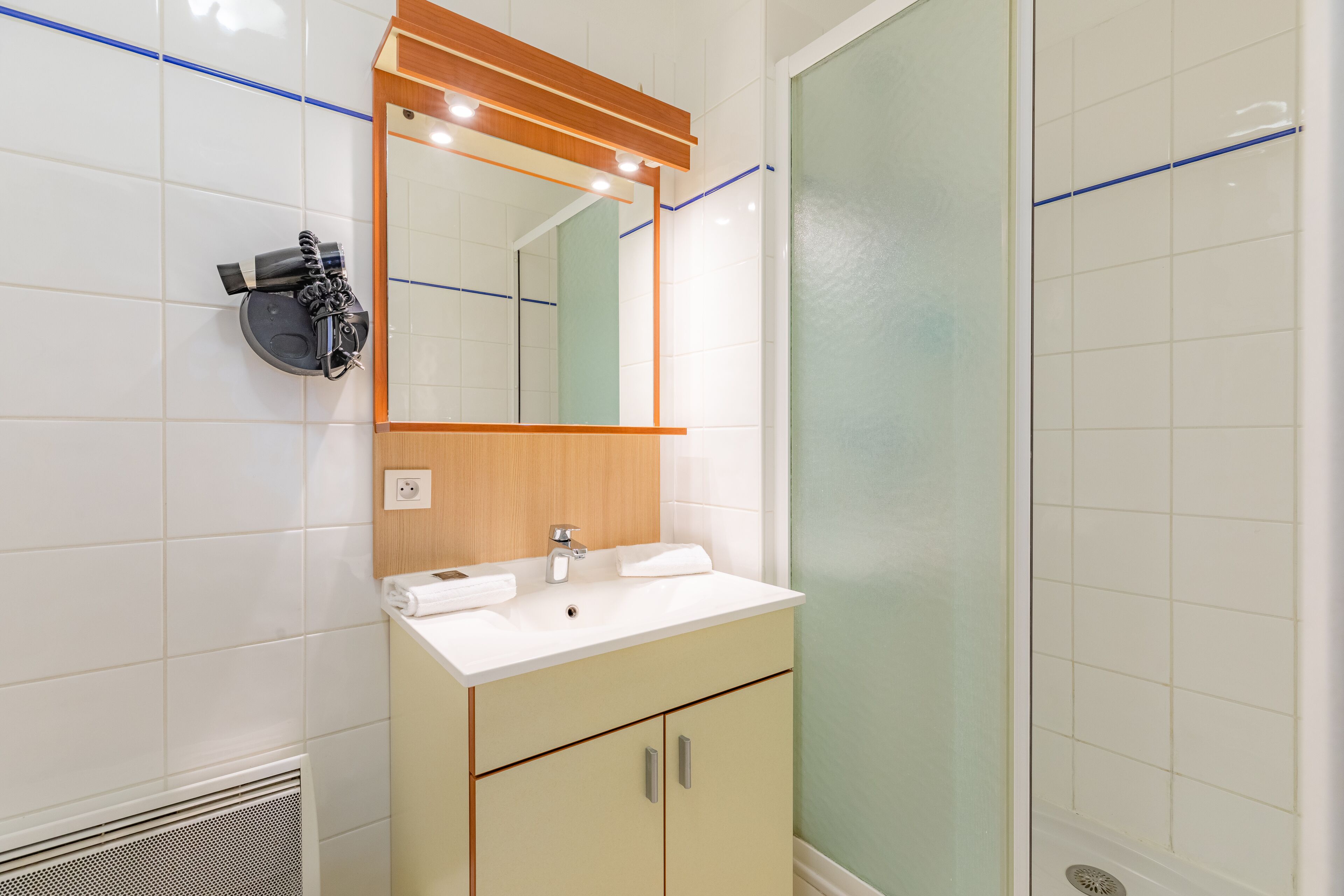 A bathroom with a white sink, wooden vanity, and a mirror with lights.