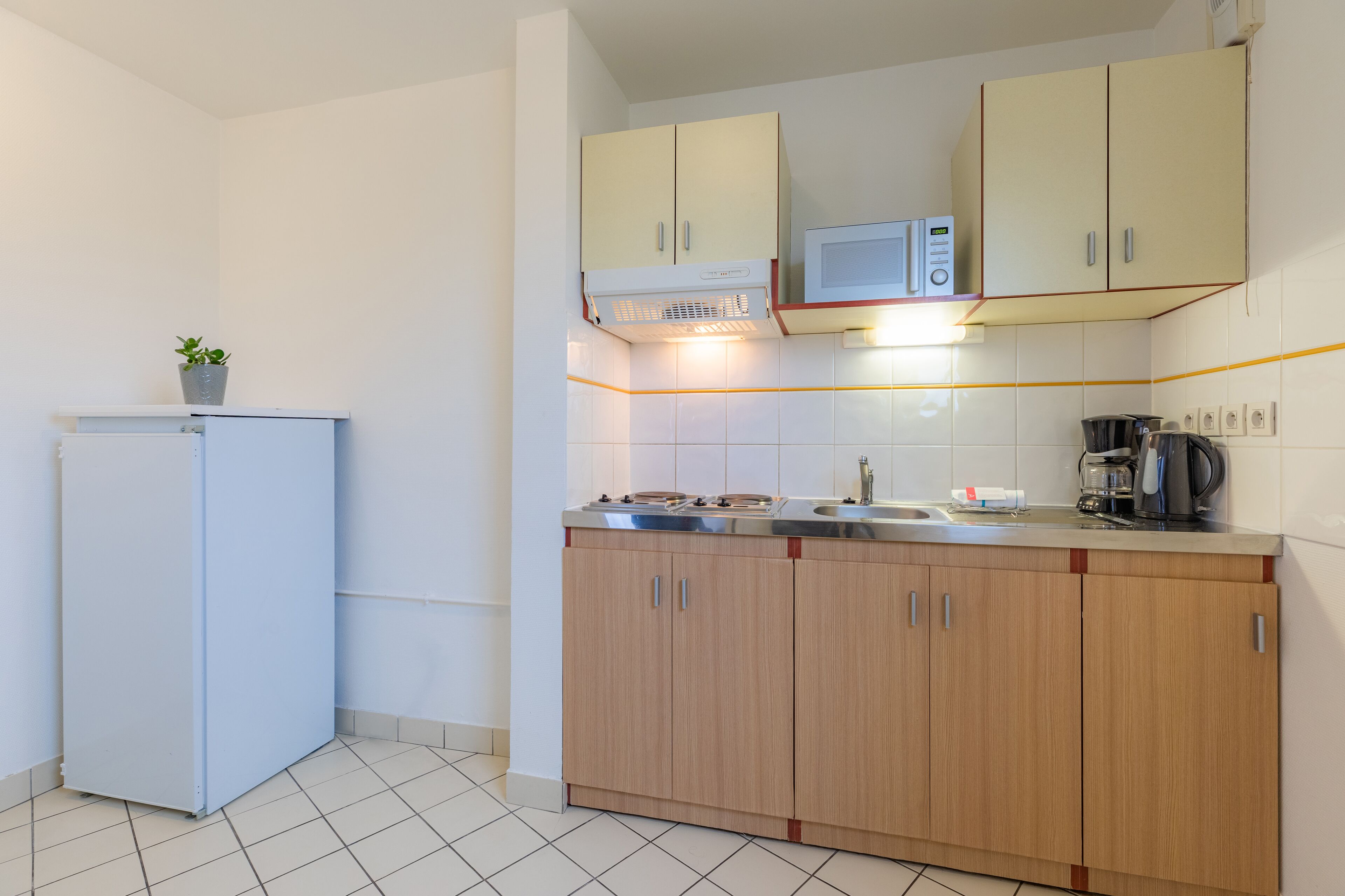 A compact kitchen with a refrigerator, microwave, stove, and wooden cabinets.