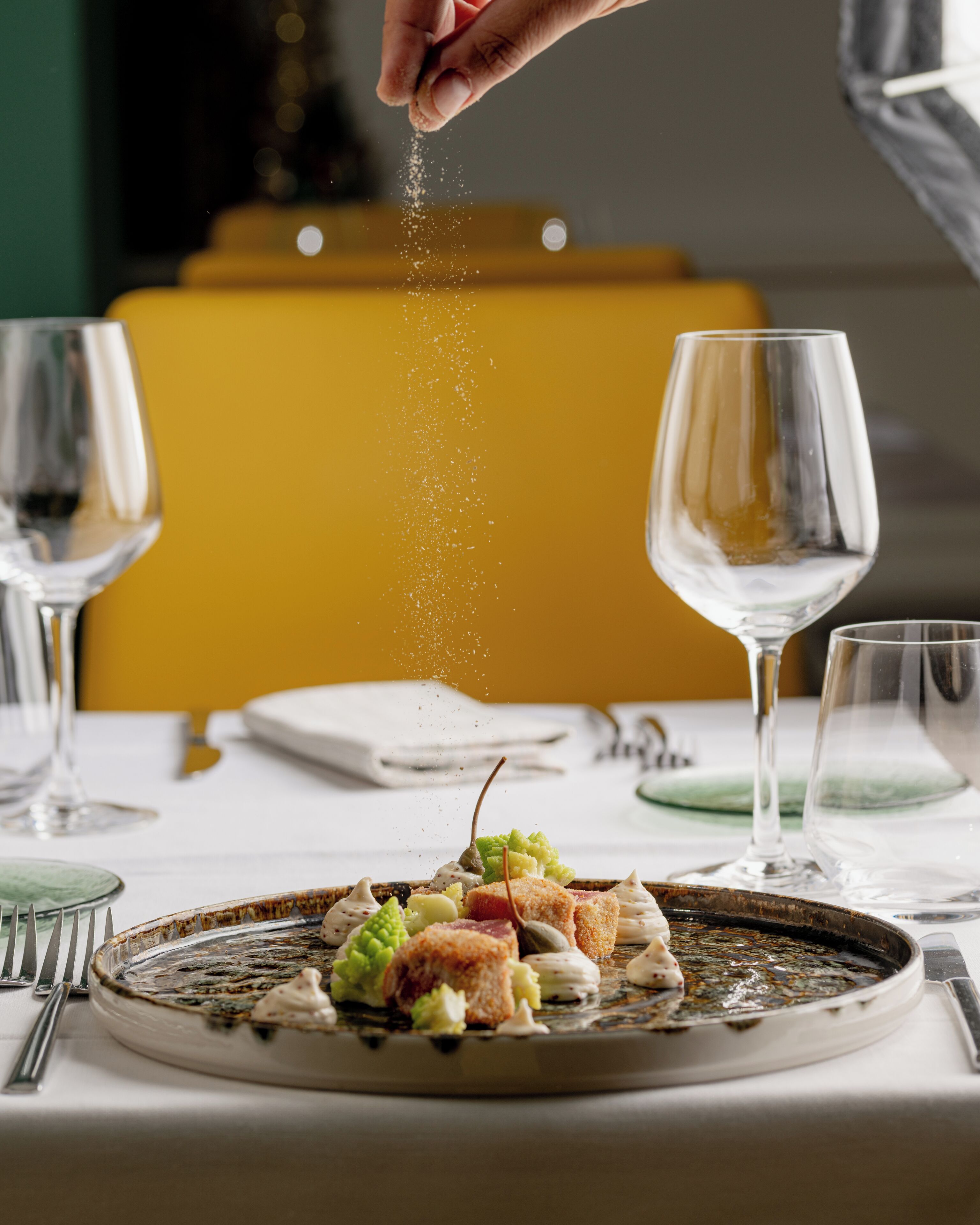 Una mesa con un plato de comida, una copa de vino y un salero.