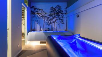A modern bedroom with a bed, a wall-mounted massage table, and a mural of trees.