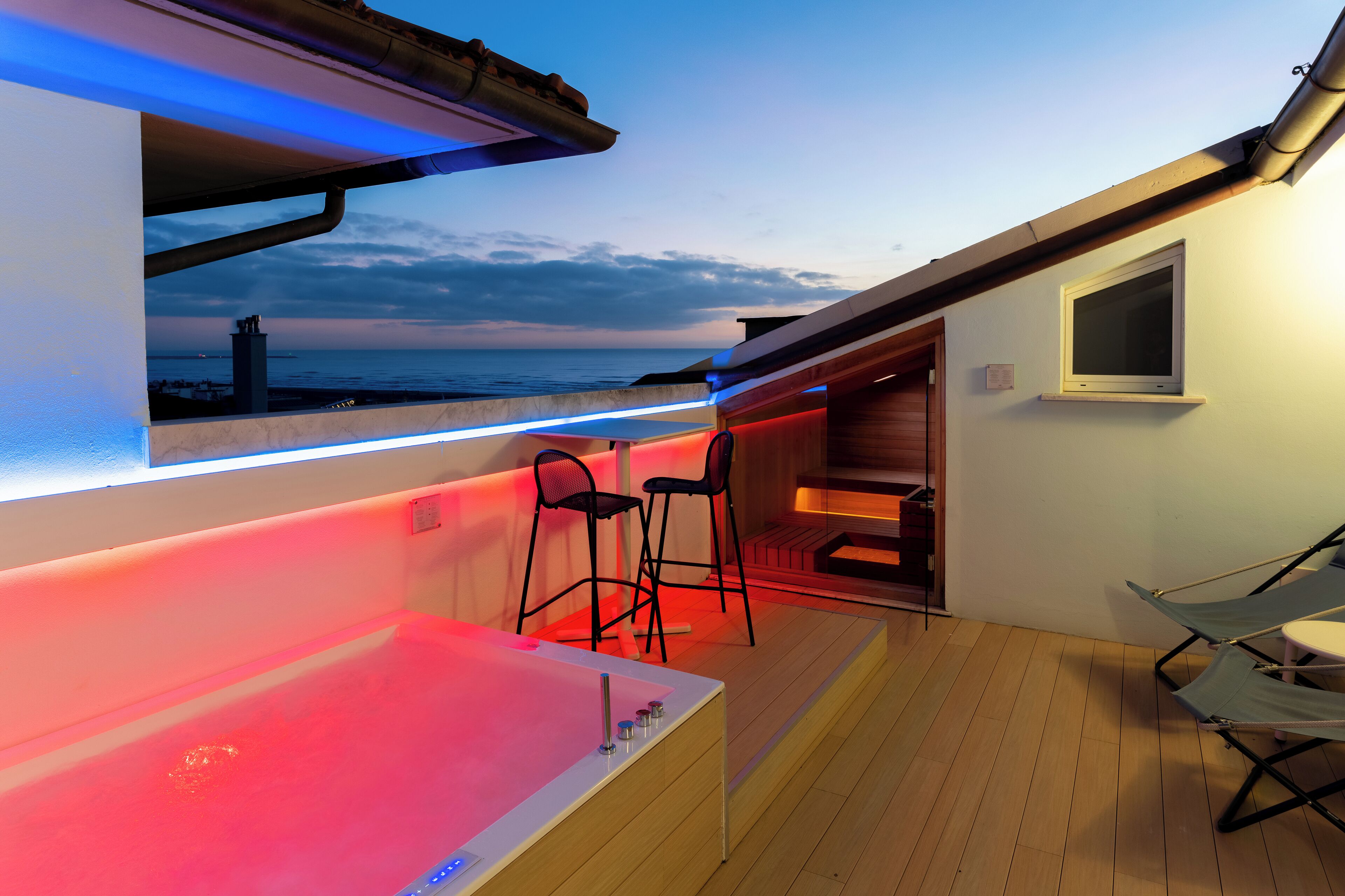 A balcony with a hot tub, seating area, and a view of the sea.