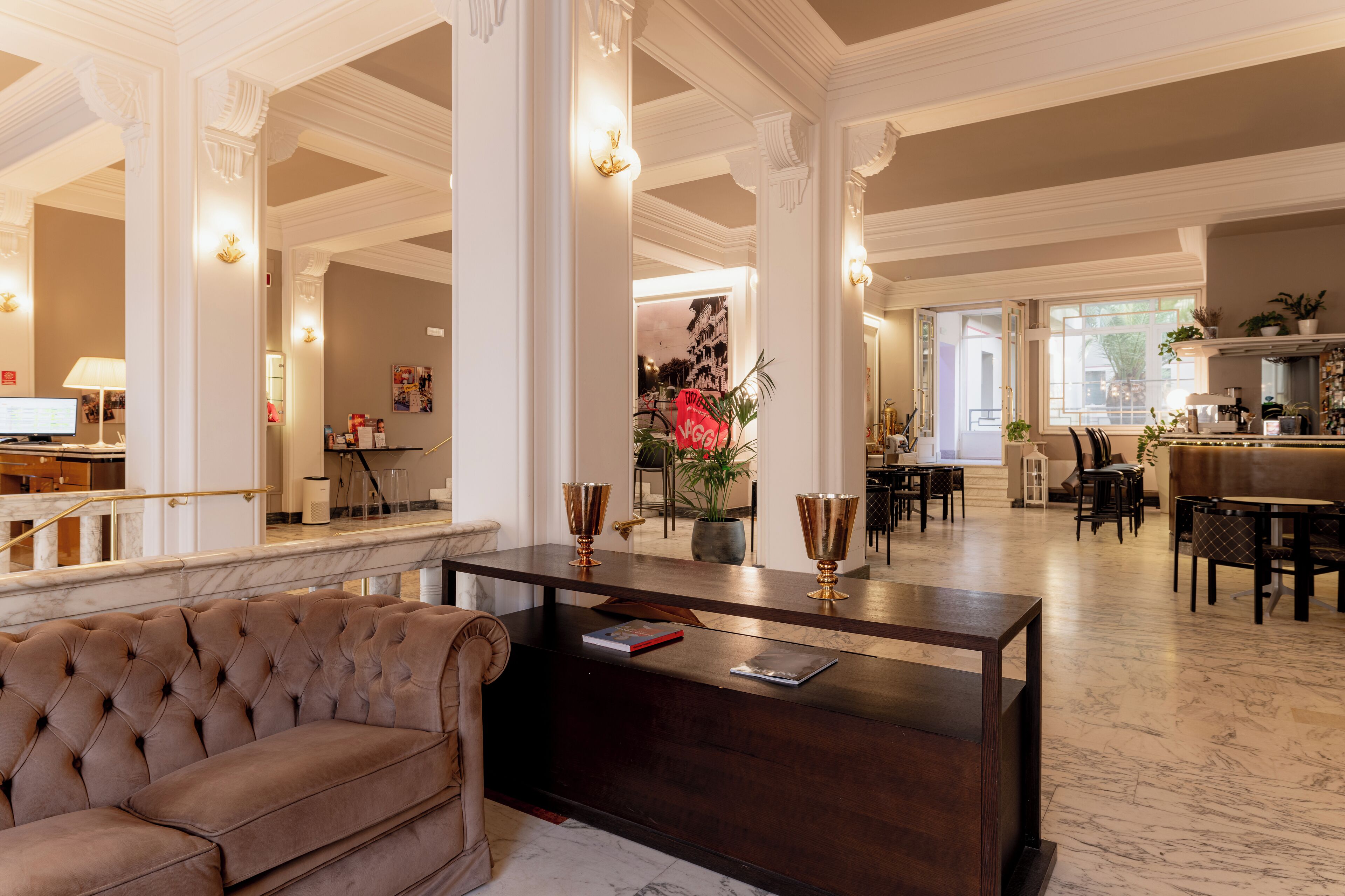 A spacious lobby with a plush sofa, a reception desk, and a dining area with tables and chairs.