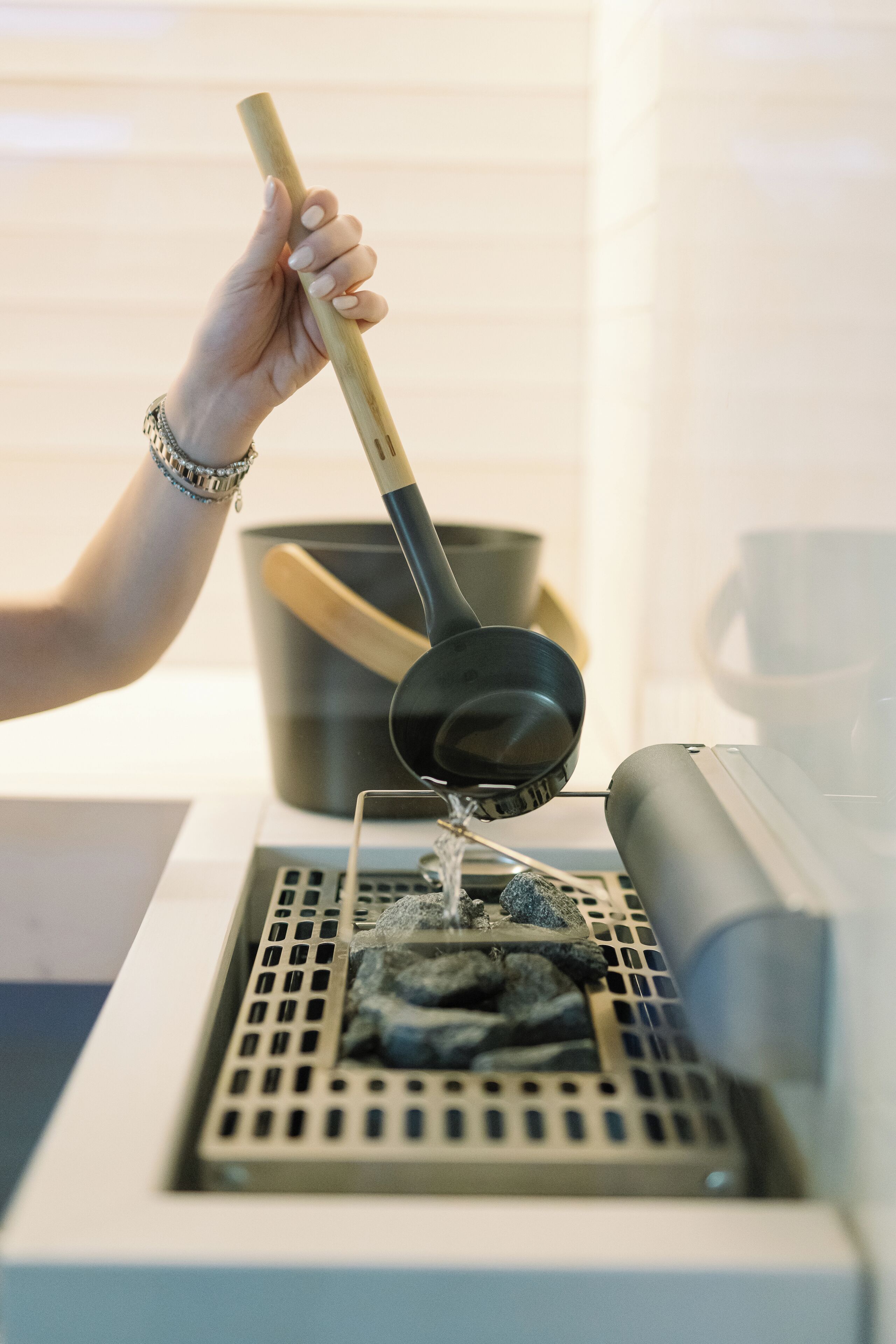 Een hand houdt een opscheplepel boven een koffiemachine en giet water in een filtermand.