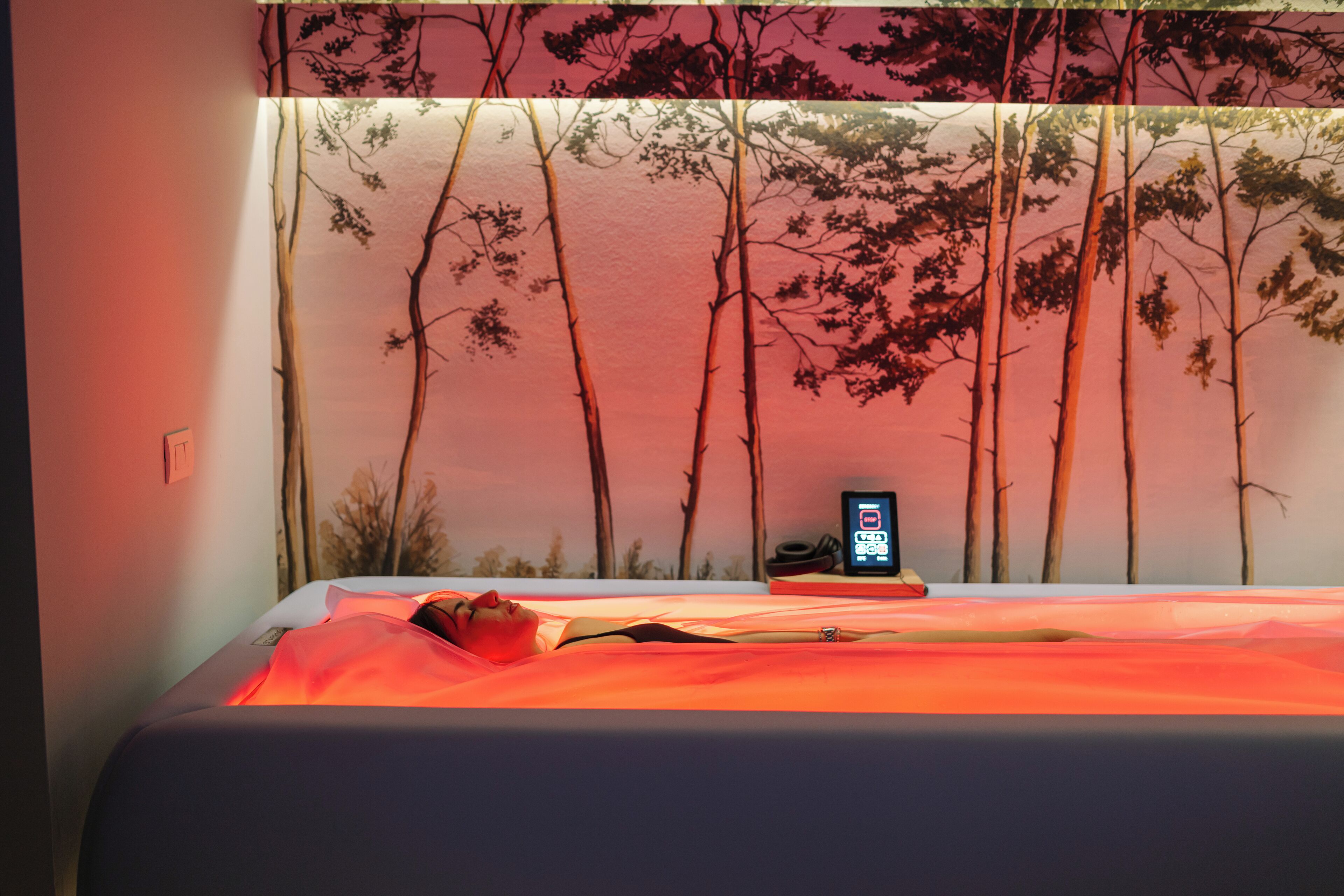 A bedroom with a bed, a nightstand, and a wall-mounted phone.