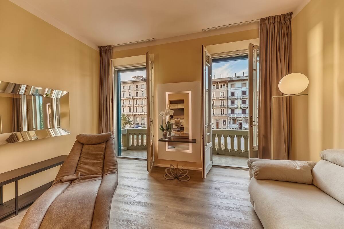 A spacious room with a massage chair, a sofa, and a view of a cityscape through large windows.