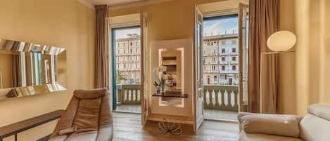 A spacious room with a massage chair, a sofa, and a view of a cityscape through large windows.