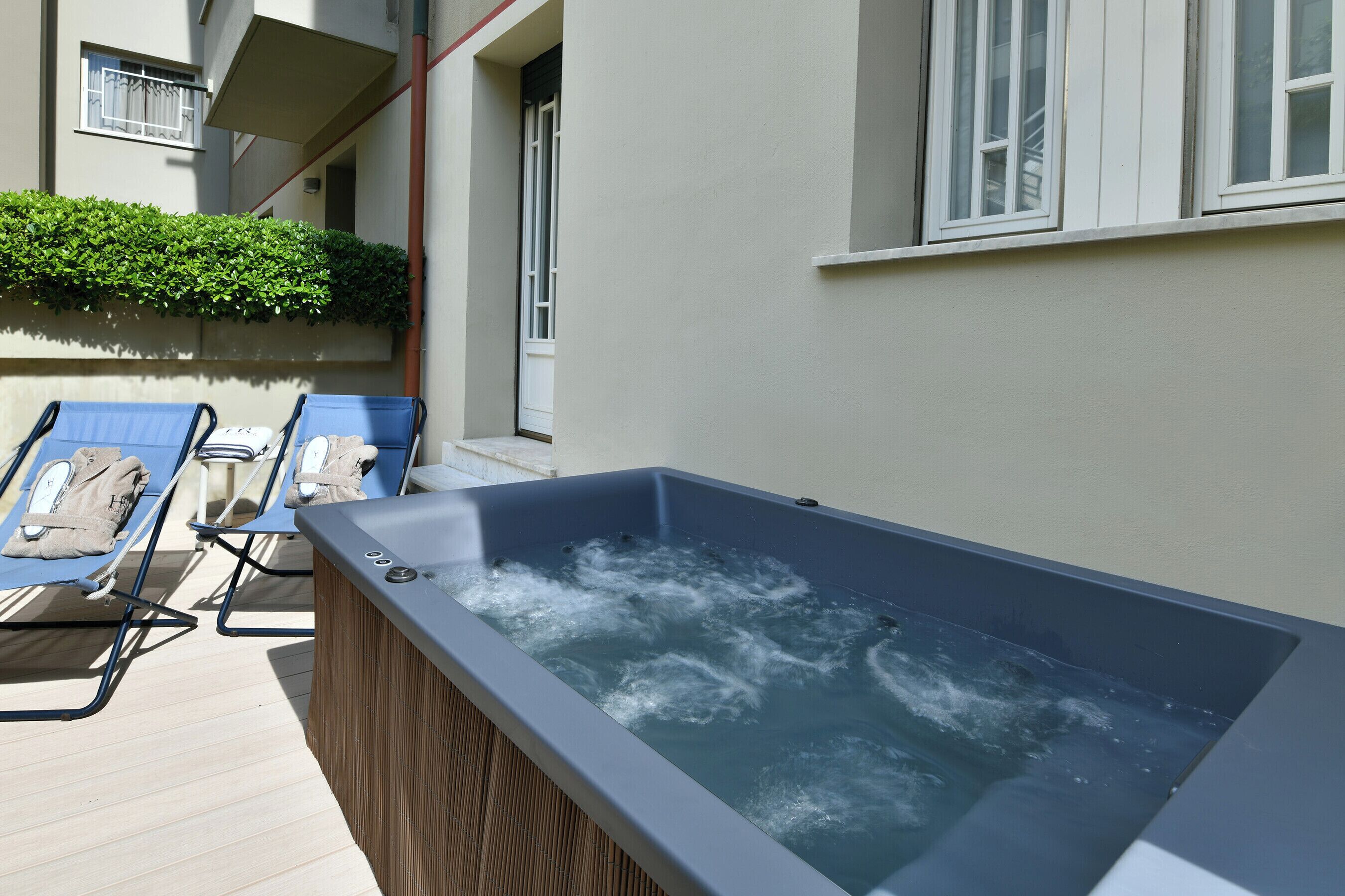 A rooftop terrace with a hot tub, lounge chairs, and a wooden deck.