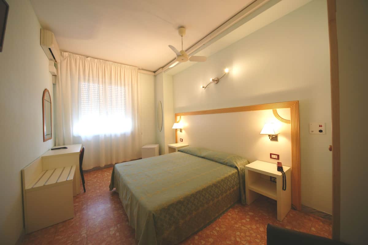 Une chambre d’hôtel équipée d’un lit, d’un bureau, d’une chaise et d’un téléphone.