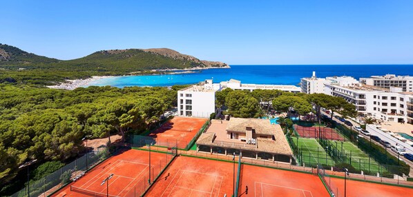A coastal view with a tennis court, buildings, and a beach. - Hotel & Spa S'entrador Playa (Capdepera)