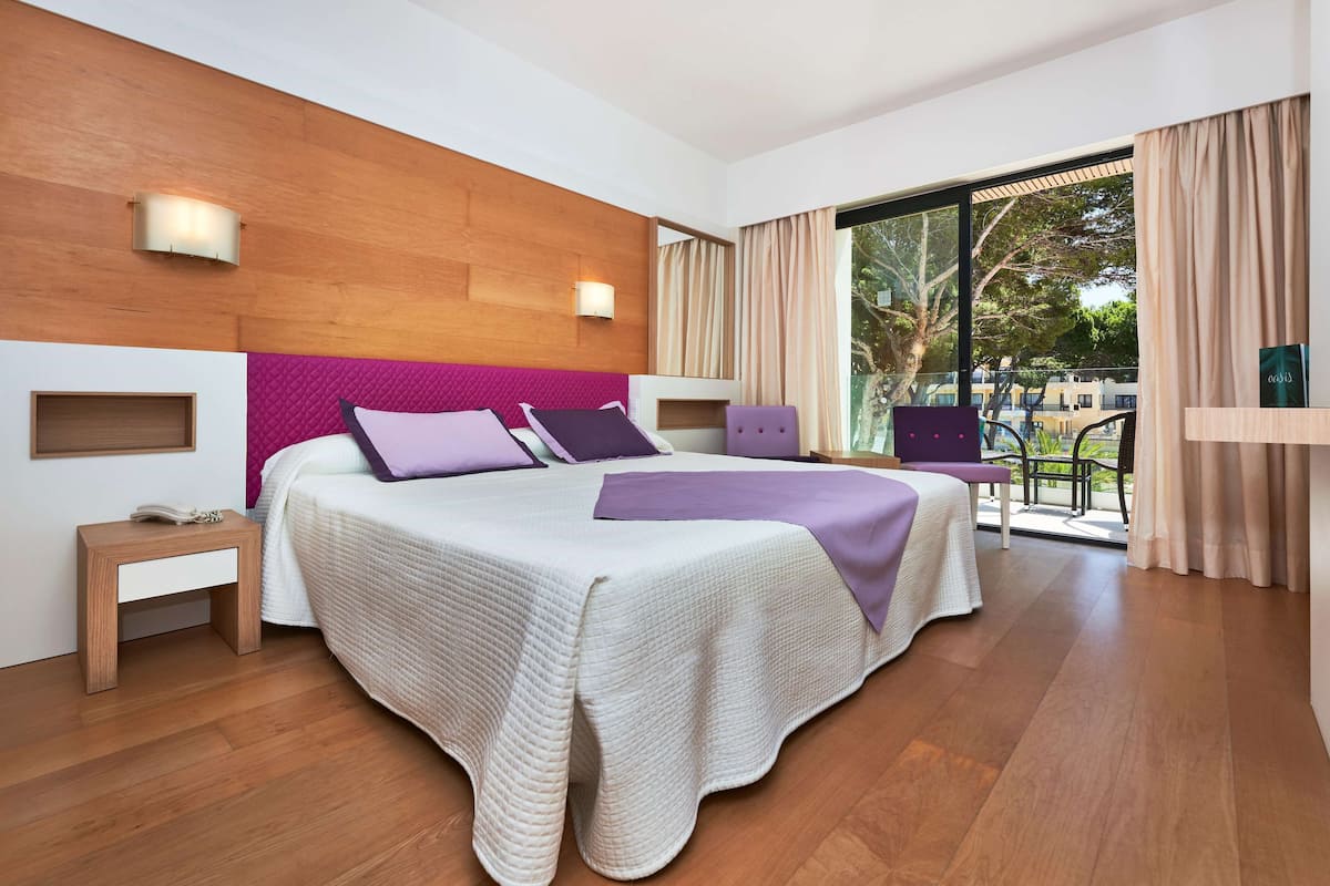 Habitación de hotel moderna con una cama grande, cabecero de madera y vistas al exterior.