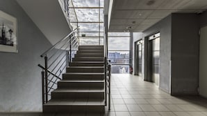 A modern interior with a staircase, metal railings, and a view through large windows. - Weiser Hotel (Wroclaw)