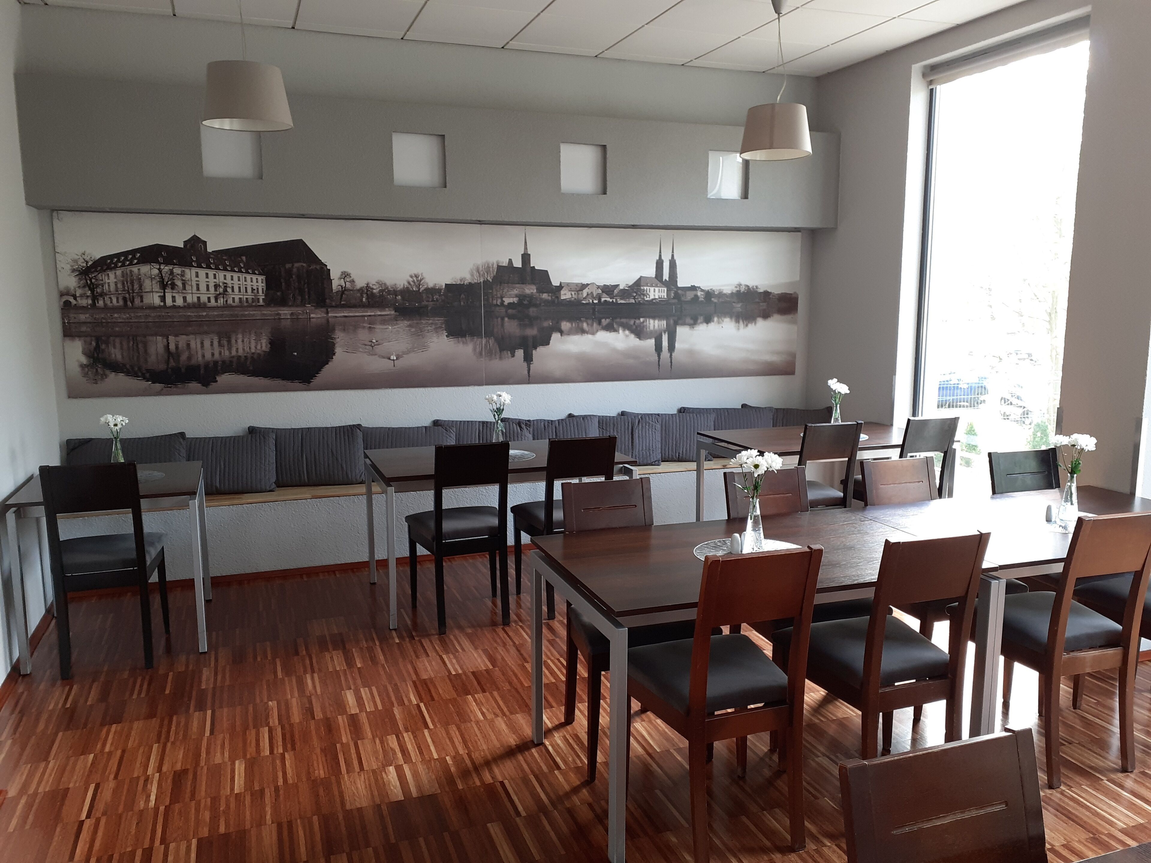 A dining area with a large cityscape mural, wooden flooring, and modern furniture.