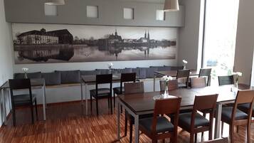 A dining area with a large cityscape mural, wooden flooring, and modern furniture.