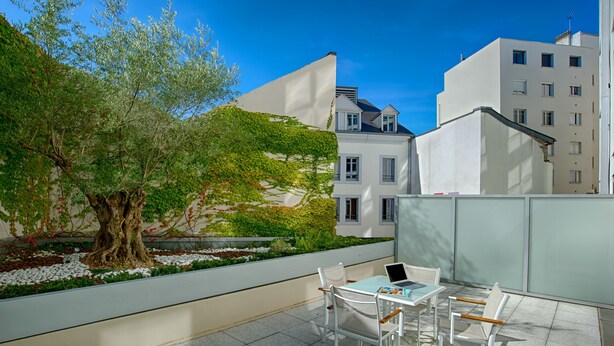 A terrace with a table and chairs, a laptop, and a tree. - Le Rex Hotel (Tarbes)