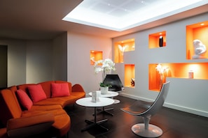 Una sala de estar moderna con un sofá modular, una mesa de centro redonda y una silla original.