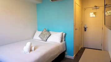 Habitación de hotel con una cama, pared decorativa azul, una puerta y un equipo de aire acondicionado.