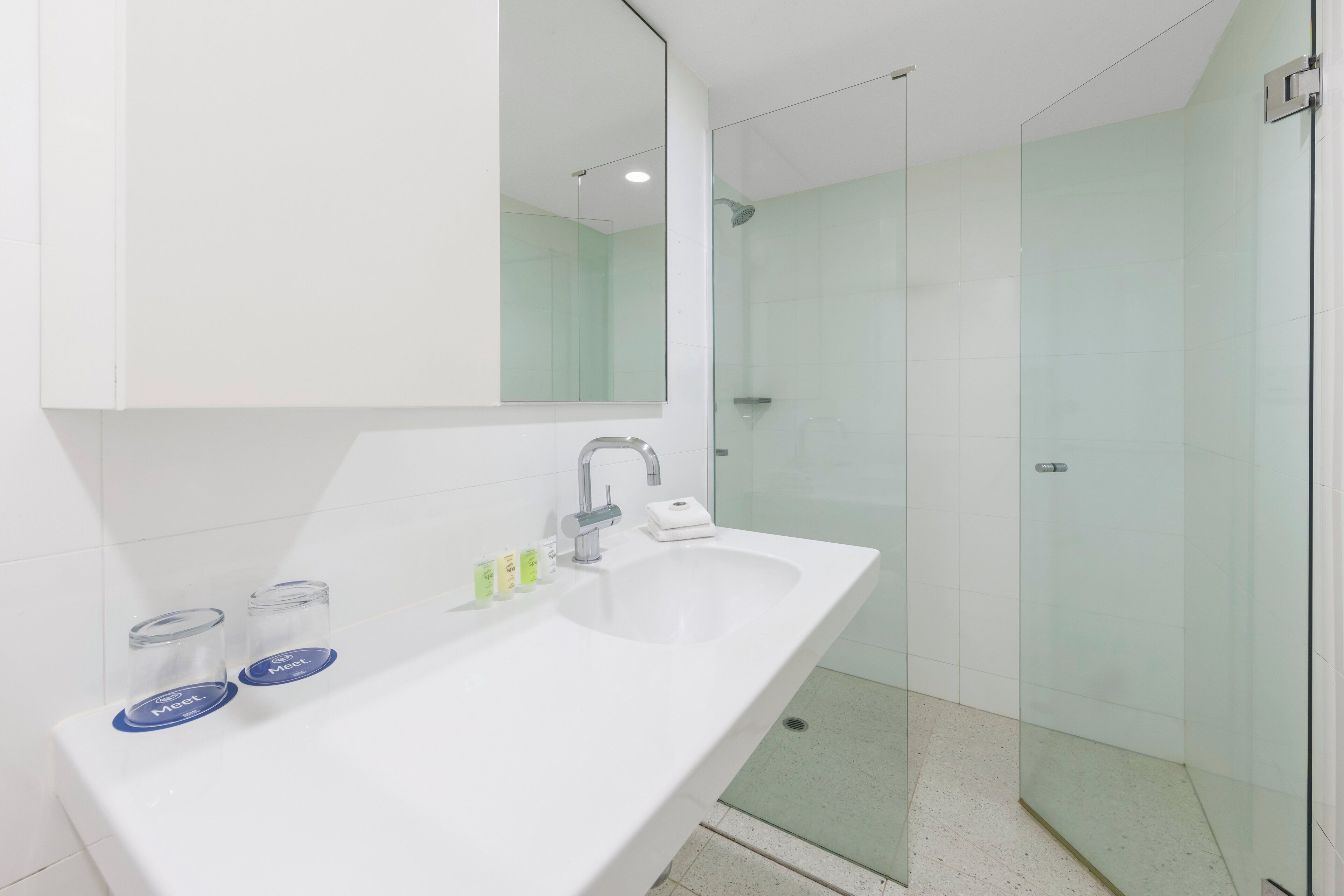 A modern bathroom with a white sink, a large mirror, and a glass shower enclosure.