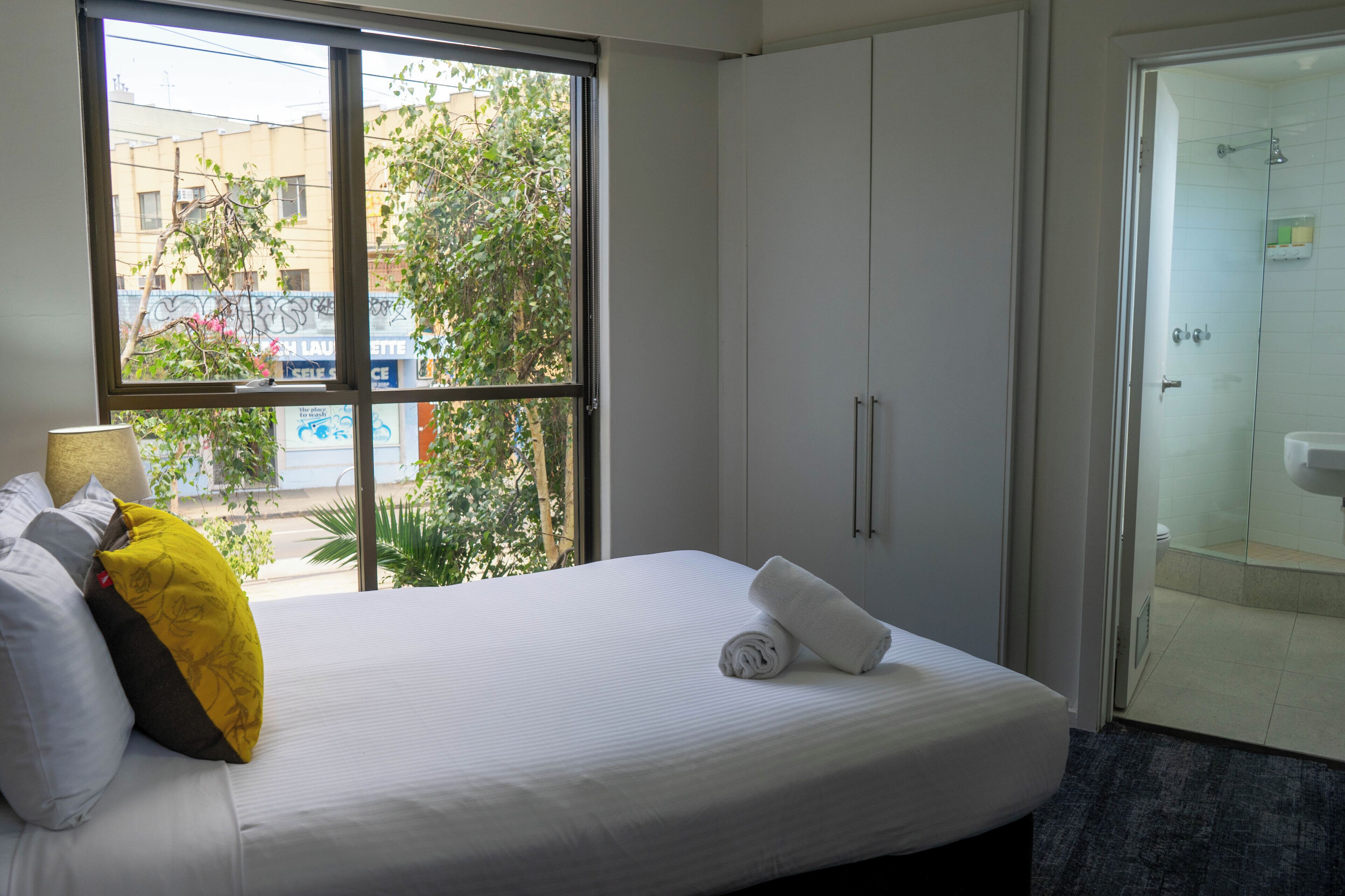 Une chambre d’hôtel avec un lit, une fenêtre et une porte donnant sur une salle de bain.